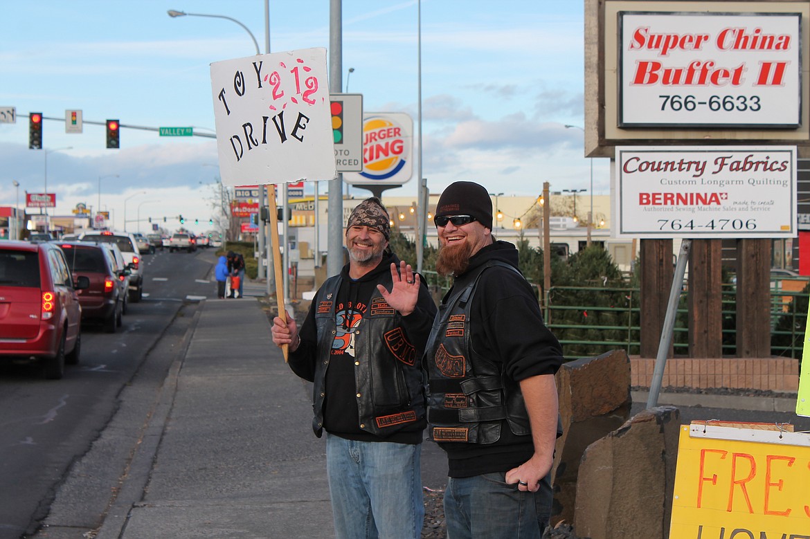 Charles H. Featherstone/Columbia Basin Herald
Unchained Brotherhood member Twitch and club president Redwood wave hello to passersby on Saturday as the club gathers to raise money and receive toy donations for needy kids.