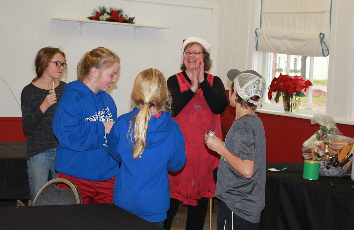 Patti Curtin celebrates with members of 4-H as they guess how many candies are in a jar, as part of the festivities during the Holiday Stroll in Superior. (Photo by Kathleen Woodford/Mineral Independent)
