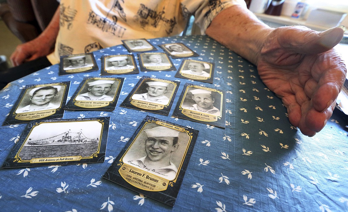This Thursday, Nov. 17, 2016 photo shows Lauren Bruner, one of just five remaining survivors of the USS Arizona during the Dec. 7, 1941, Japanese attack of Pearl Harbor, with trading cards depicting his shipmates, at his home in La Mirada, Calif. Burns covered most of his body after Japanese planes bombed Bruner's ship. He spent seven months recovering in the hospital, and returned to fight in more battles. (AP Photo/Reed Saxon)