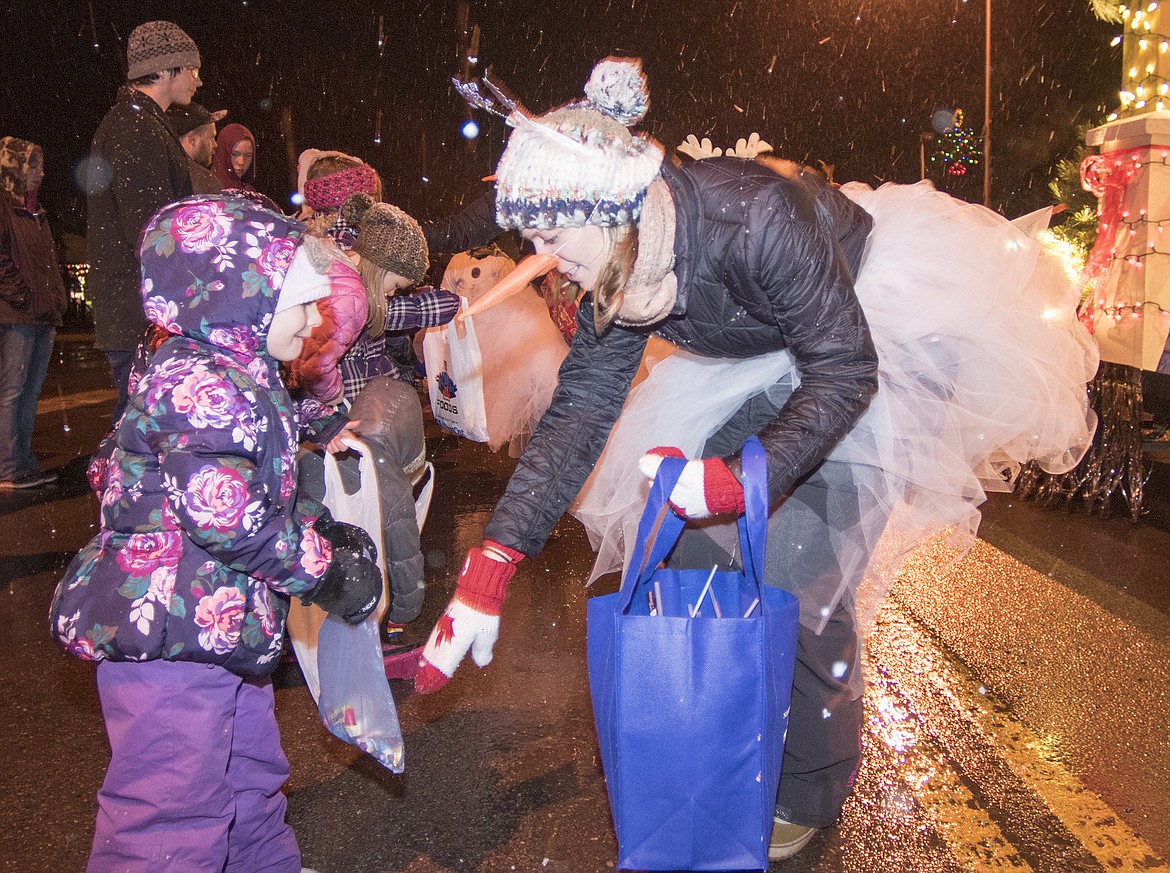 A snowgirl hands out candy to children.