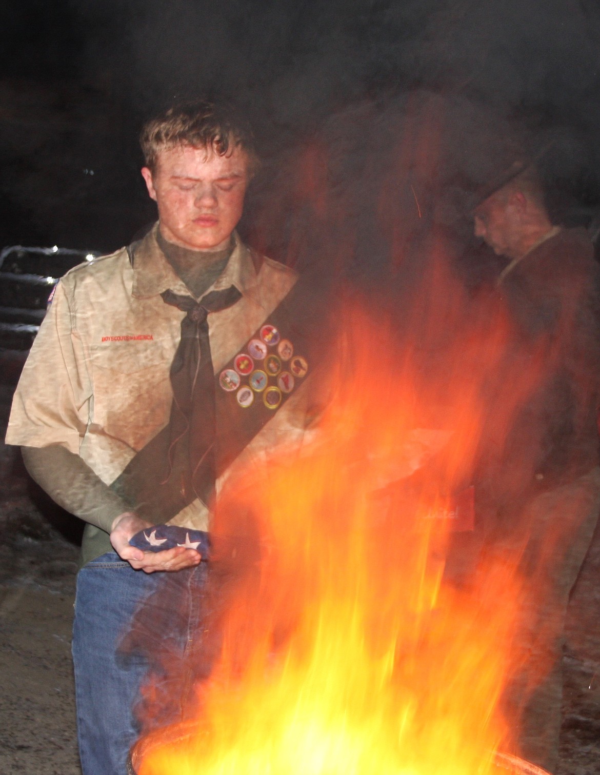 NOAH HATHORNE, JR. brings a retired flag to the fire. (Lisa Larson/Clark Fork Valley Press)