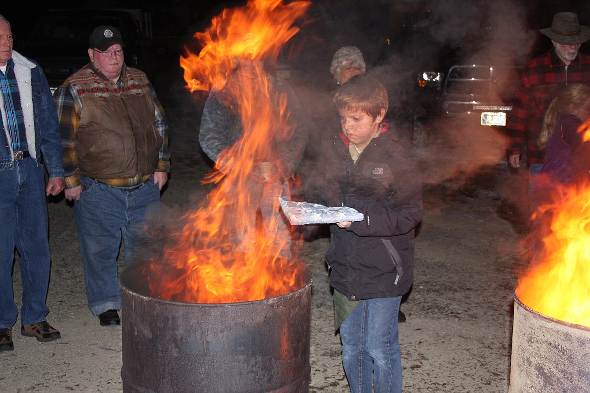 A YOUNG Boy Scout brings a retired flag to the fire. (Lisa Larson/Clark Fork Valley Press)