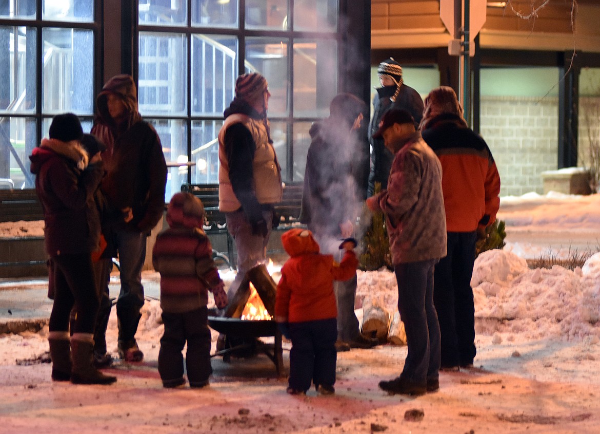 Folks warm up beside the fire outside the Great Northern Brewing Co. during Friday night's Christmas Stroll.