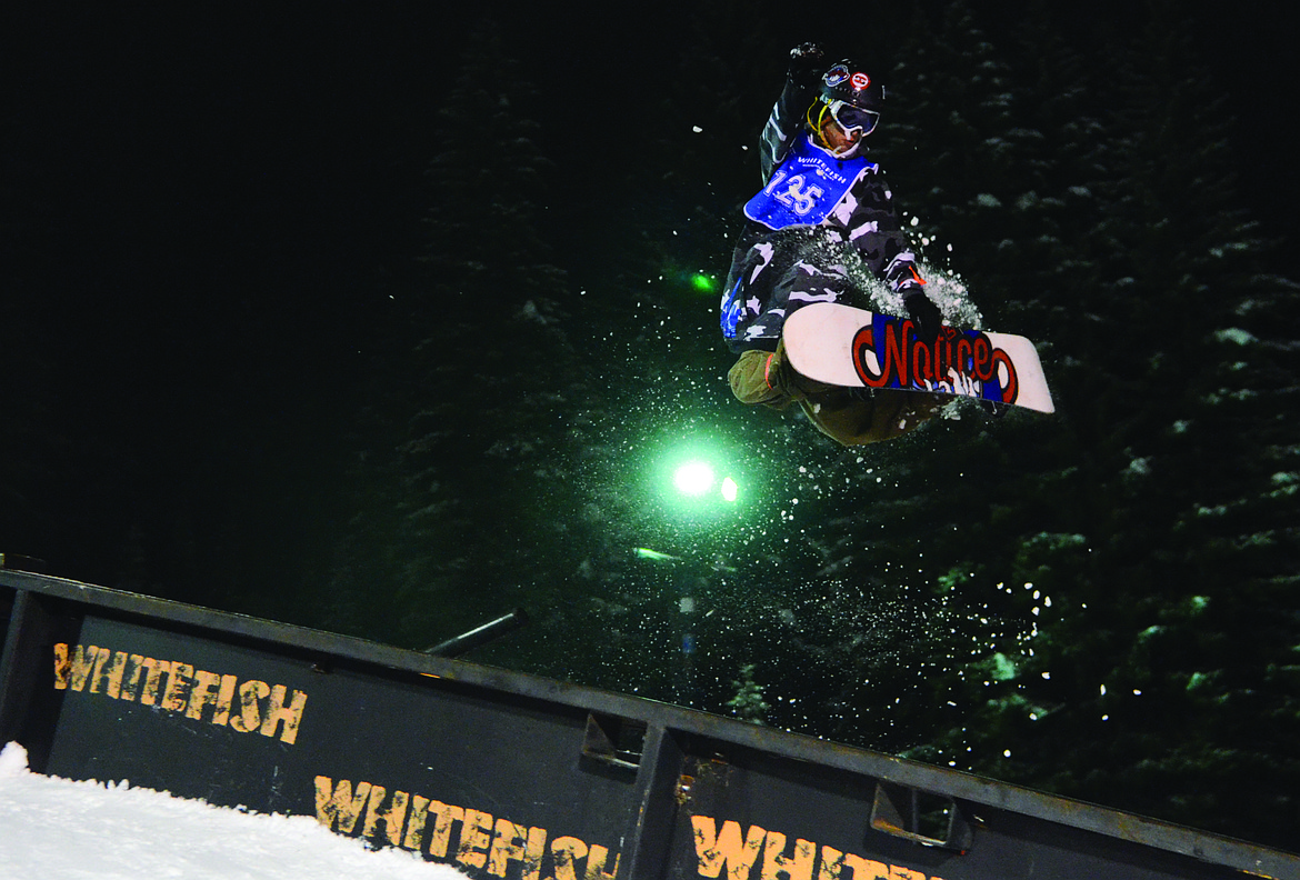 A SNOWBOARDER grabs his board during the New Years Eve Rail Jam at Whitefish Mountain Resort.