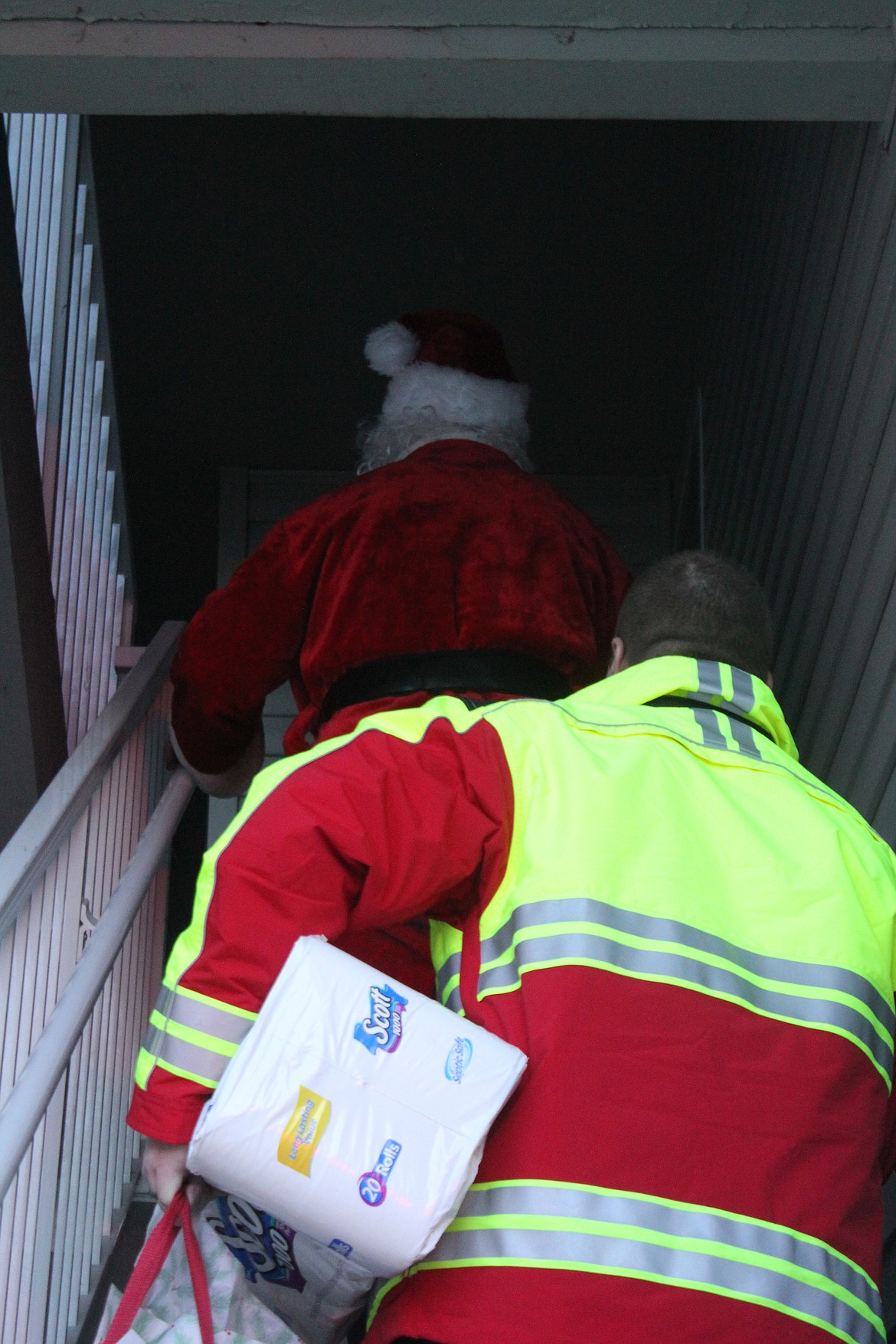 Richard Byrd/Columbia Basin Herald
Moses Lake firefighters, and Santa, make their way up some stairs to deliver presents to a local family in need.