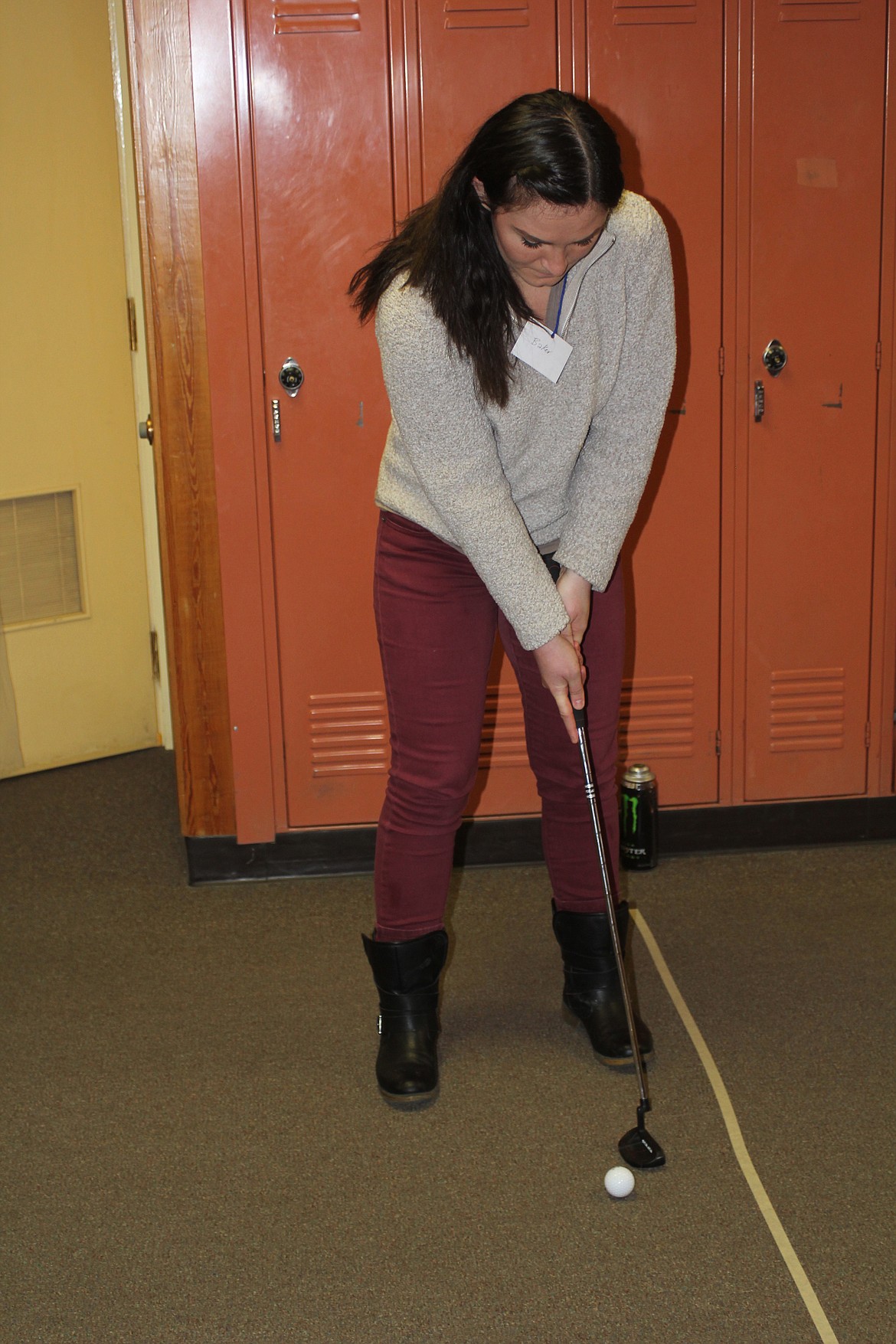 Jordan Plutt, the librarian at Plains school, is taking her stance at the golf ball putting game. (Douglas Wilks/Clark Fork Valley Press)