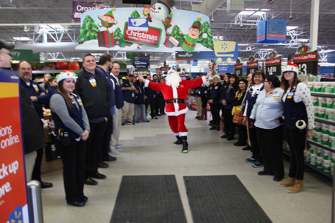 Robbie Rowe/The Sun Tribune - The staff at Walmart in Othello gather with Santa at the entrance to greet the kids and cops participating in the annual Shop With A Cop event Saturday.