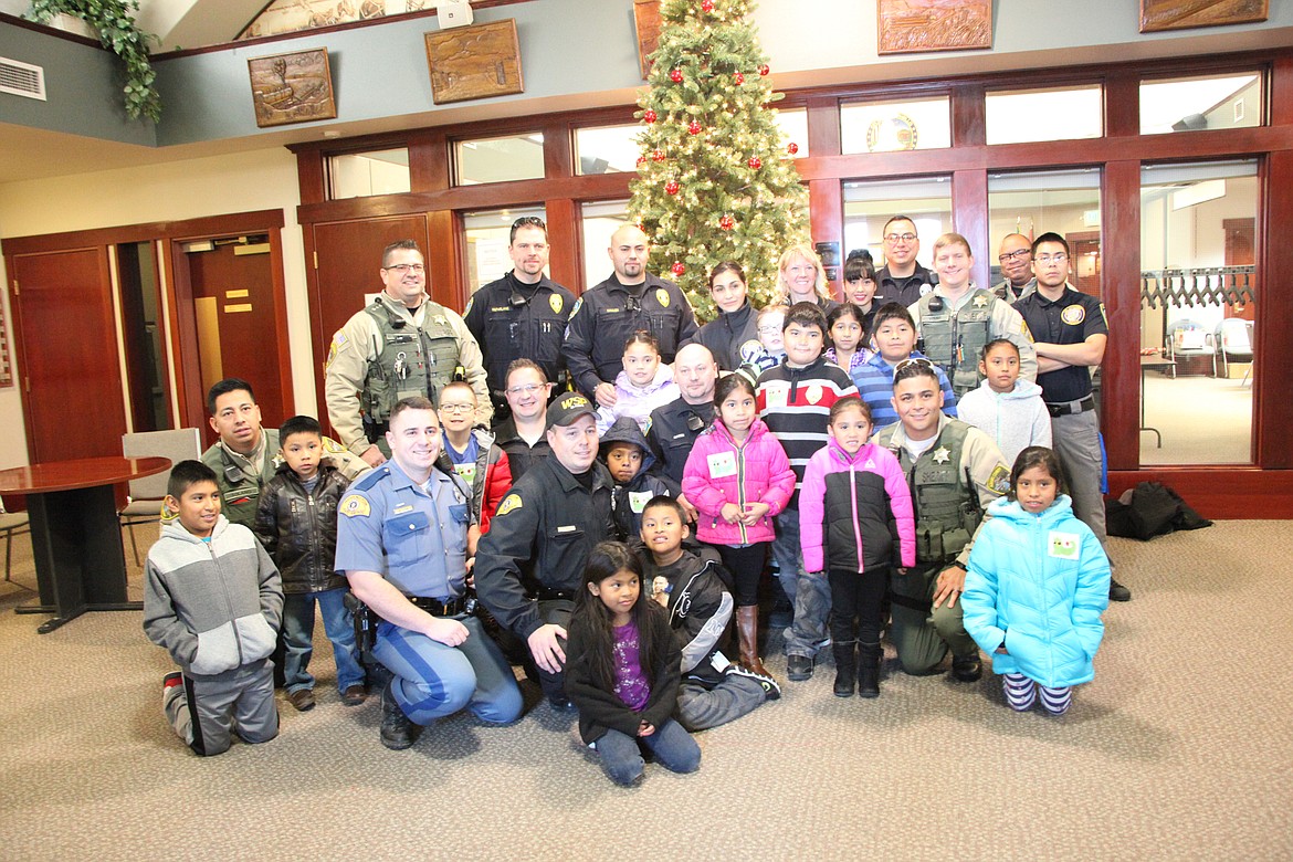 Robbie Rowe/The Sun Tribune - Officers and their shopping buddies pose for a photo before heading out Saturday for the annual Shop With A Cop event.