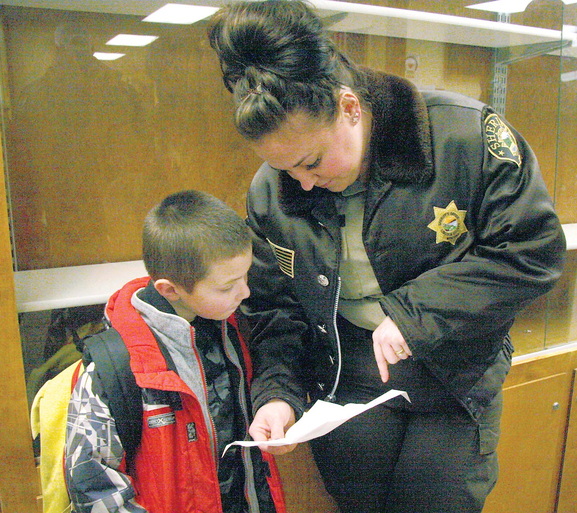 Riley Stoltz and Sheriff&#146;s Deputy Chanel Geer going through Stoltz&#146;s Christmas list before venturing out for the annual Shop with a Cop. (Bethany Rolfson/TWN)