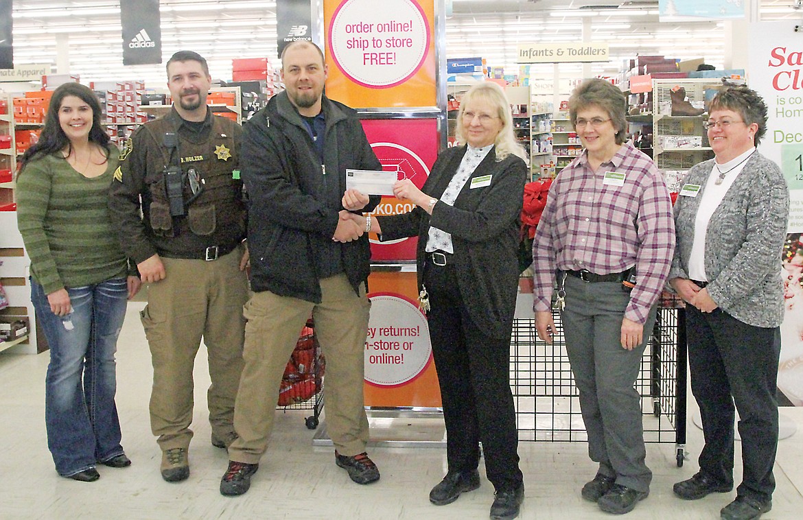 Detective Brad Dodson receives a $1,000 check from Shopko Manager Marion Craig Friday with Loni Harmon, left, Sgt. Brandon Holzer,  Dodson, Craig, Cindy Beaulieu and Karen Warner. (Paul Sievers/TWN)