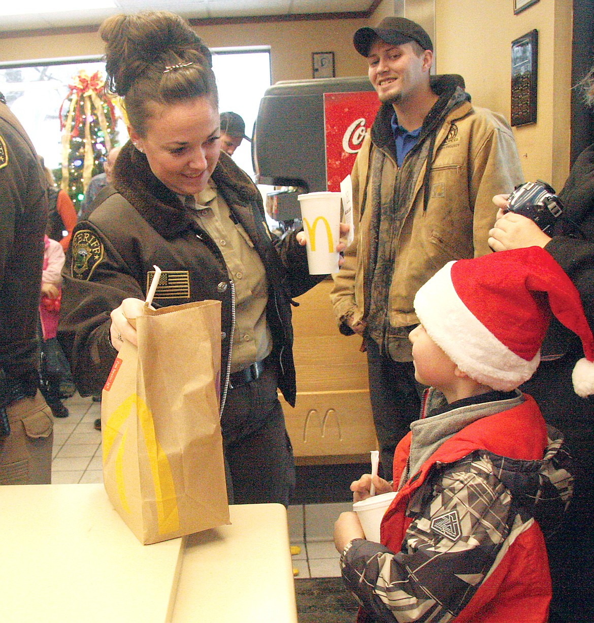 Sheriff&#146;s Deputy Chanel Geer handing Riley Stoltz his meal at McDonald&#146;s as part of the fourth annual Shop with a Cop. (Bethany Rolfson/TWN)
