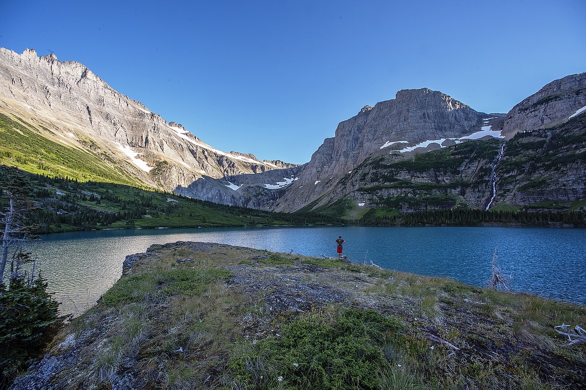 A hiker looks over a high mountain lake in Glacier National Park.