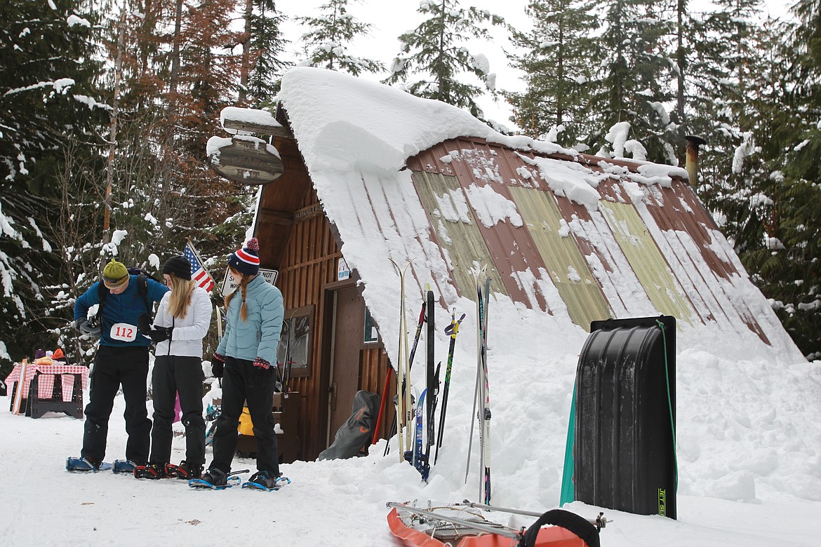 DEVIN HEILMAN/Press
Mike Bailey secures his backpack in front of the Fourth of July Recreation Area warming hut Saturday as daughters Grace, 14, center, and Allie, 12, prepare for a snowshoeing adventure with their dad.