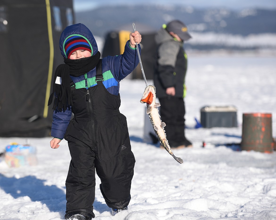 Reece Banner, 4, carries the pike he caught during the during the Kalispell Sunriser Lions Club's 46th annual ice fishing derby on Saturday at Smith Lake. (Aaric Bryan/Daily Inter Lake)