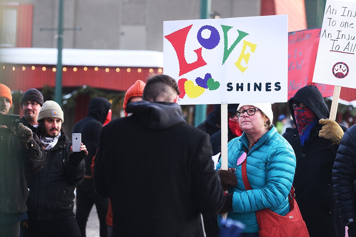 Rebecca Norton of Whitefish carries a sign that reads &#147;Love Shines&#148; during a gathering in downtown Whitefish on Monday afternoon. (Brenda Ahearn photos/Daily Inter Lake)