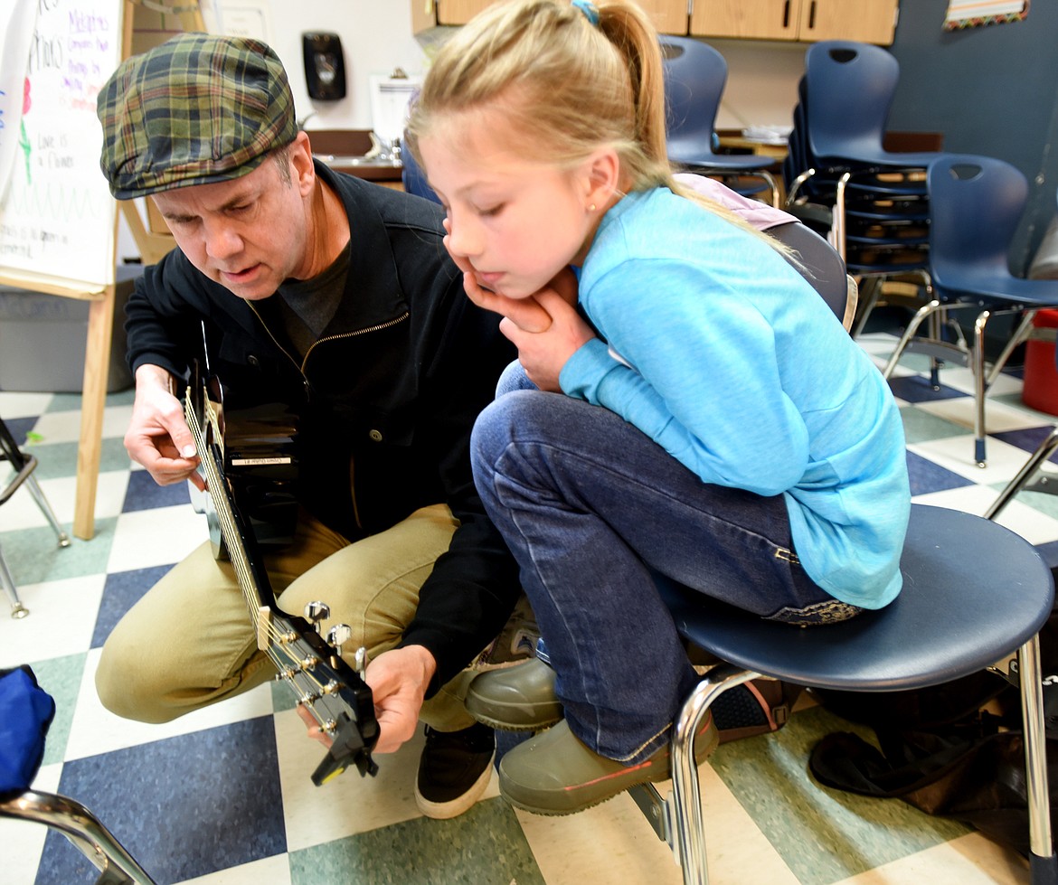Tim Torgerson shows Ione Plummer, 9, of Bigfork, how to tune her guitar. (Brenda Ahearn photos/Daily Inter Lake)