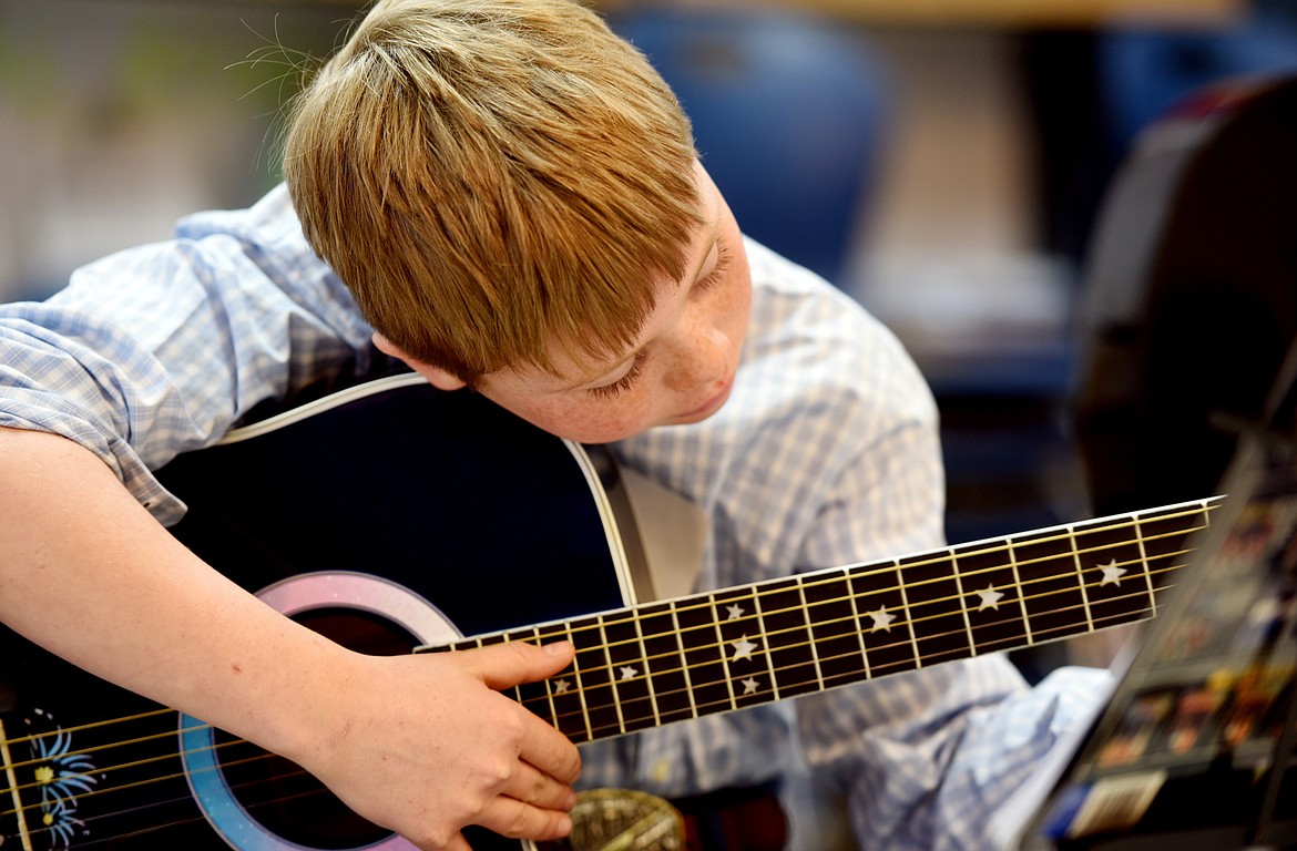 Sam Plummer, 10, of Bigfork, works on his finger positions on Monday, January 9 in the Bigfork ACES Beginning Guitar Class at Bigfork Middle School.(Brenda Ahearn/Daily Inter Lake)