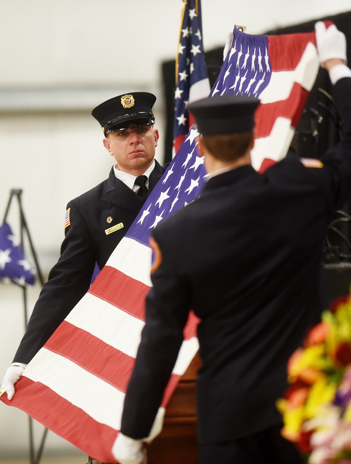 Josh Charles of the Bozeman Fire Department helps fold the flag that had been draped over Ben Parsons&#146; casket at the end of the funeral on Thursday, January 12, at the Northwest Montana Fairgrounds. Firefighters, law enforcement officers and first responders from around the state came to attend and take part in the funeral.&#160;
(Brenda Ahearn/Daily Inter Lake)