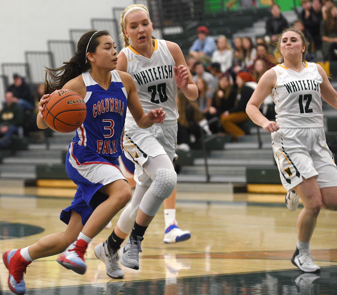 Columbia Falls guard Dani Douglas drives past Whitefish defenders Bella Wilson (20) and Libby Nagler (12) for a basket in the Wildkats&#146; 66-22 win in Whitefish on Thursday. (Aaric Bryan/Daily Inter Lake)