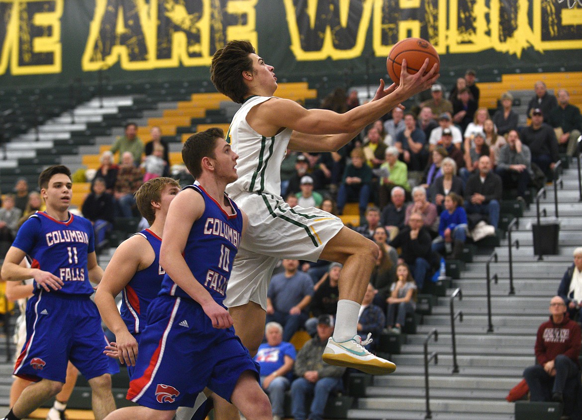 Whitefish sophomore Lee Walburn flies past the Columbia Falls defenders for a basket during the first quarter. (Aaric Bryan/Daily Inter Lake)