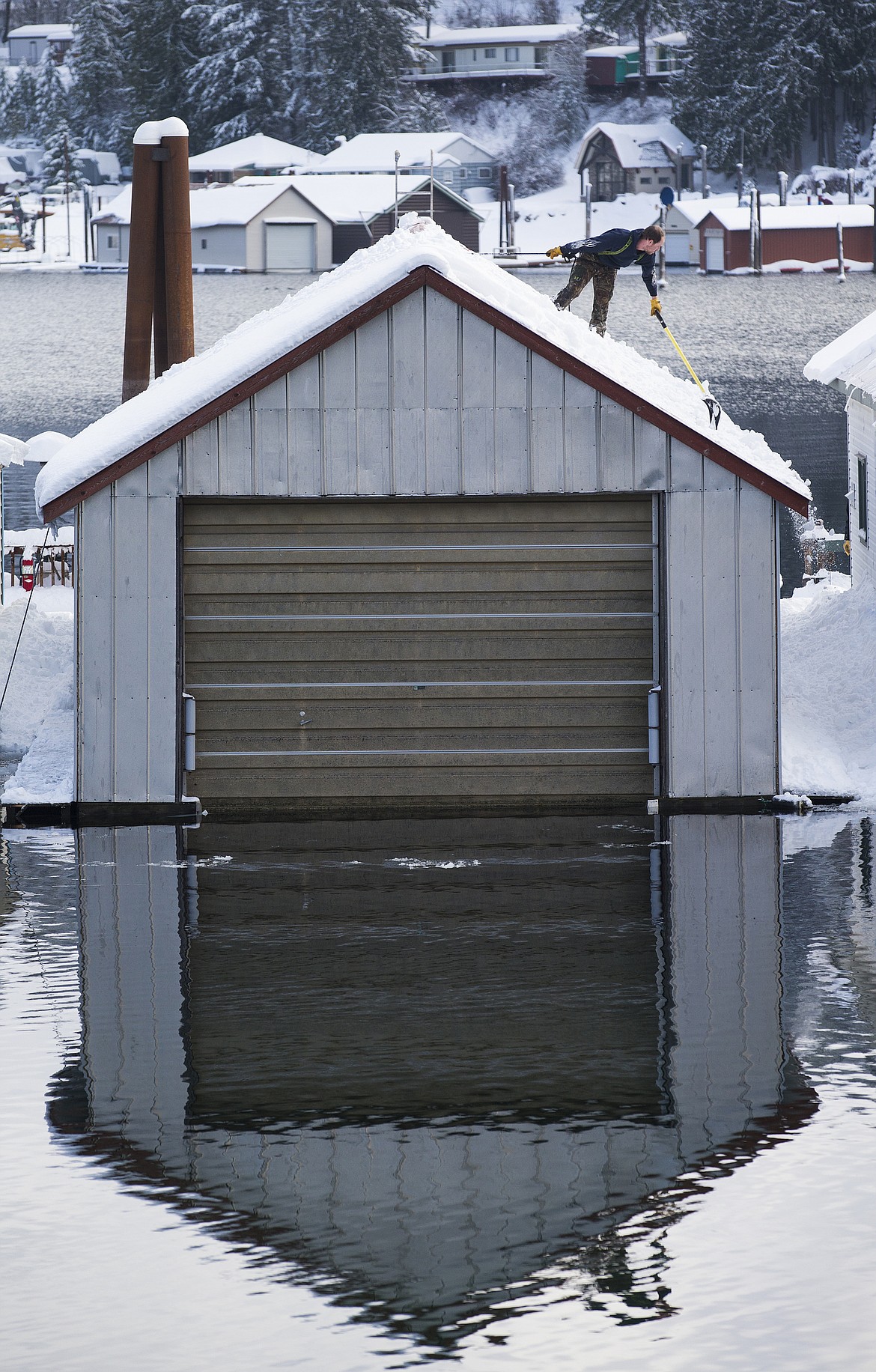 LOREN BENOIT/PressRaymond Lee shovels snow from the roof of a floating home in bayview, Idaho on Tuesday.