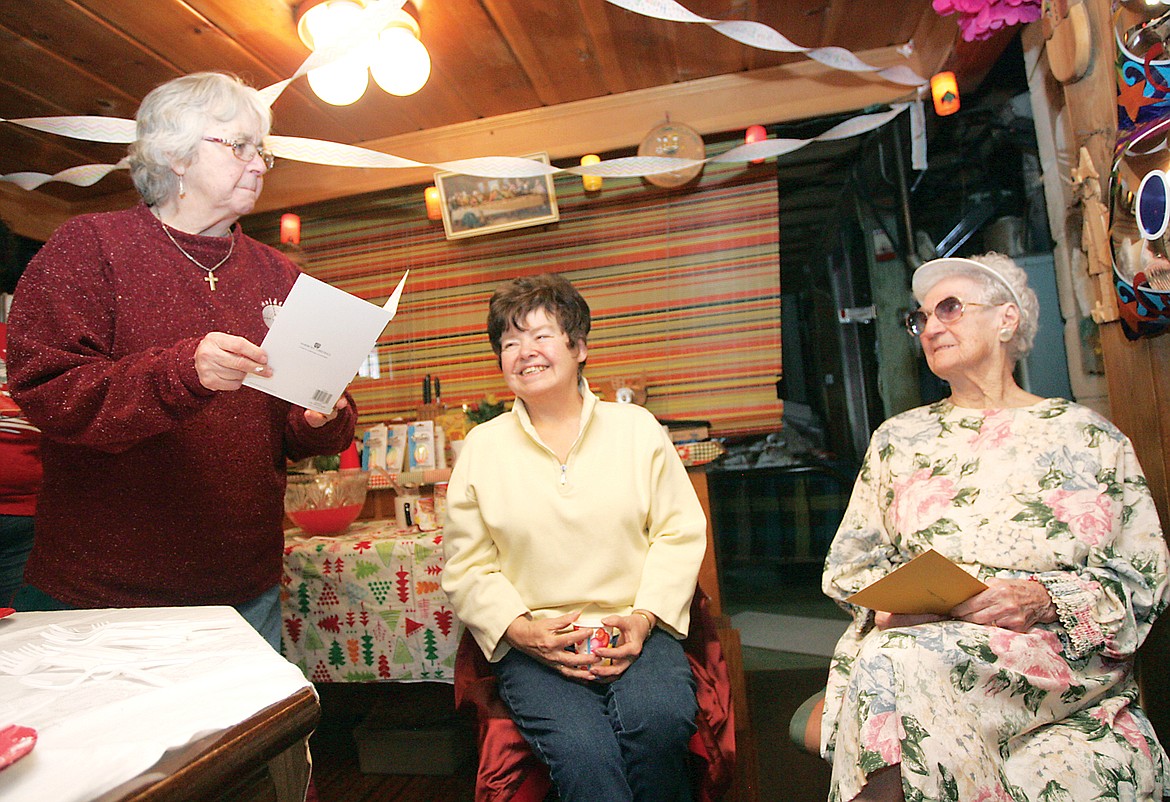 Chloe Adamson, left, reads aloud one of the many birthday cards as Vernie Tiwater and birthday girl Mildred Whitehouse listen during Mildred's 100th birthday party Thursday, Jan. 5. (Paul Sievers/TWN)