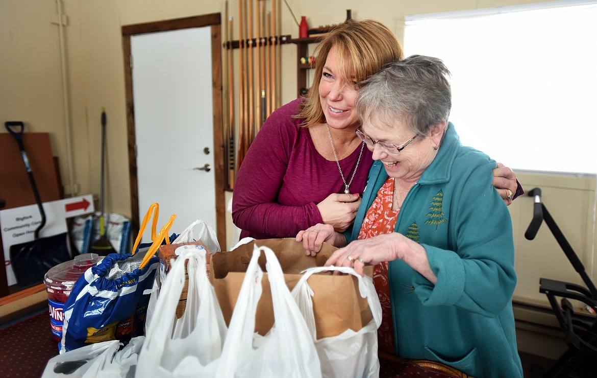 KIM ROSE, left, hugs Linda Russell as she arrives with bags of snacks for the children who will soon be arriving at Threads in Bigfork on Thursday afternoon. Threads is a project started by the Bigfork Ladies Service Club that provides students with clothing and hygiene products. (Brenda Ahearn/Daily Inter Lake)