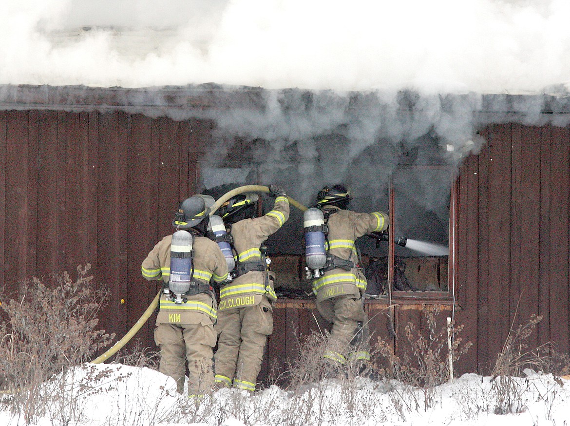 Timothy Kim, left, Jason Colclough and Jason Sunell work to extinguish the fire at 2624 E. Fifth Street Friday afternoon. (Paul Sievers/TWN)