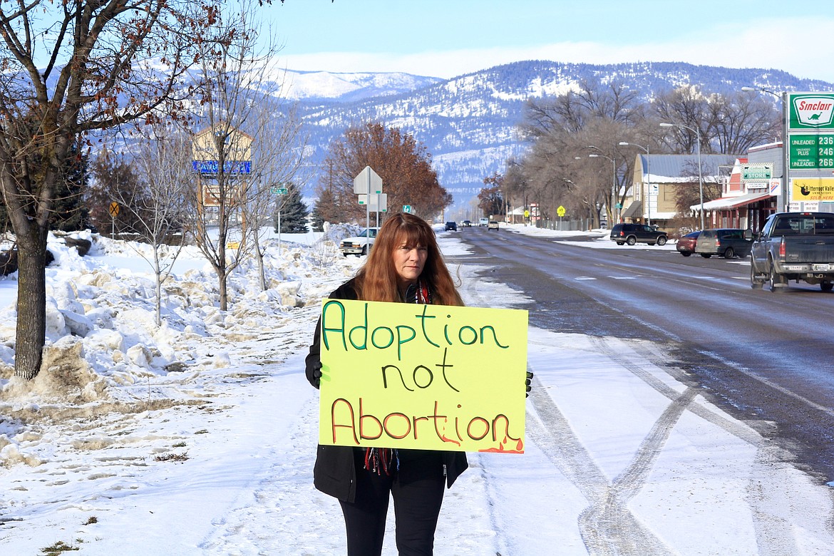 PLAINS RESIDENT Terrie Woods stands with a sign near Montana Highway 200. (Douglas Wilks/Clark Fork Valley Press)