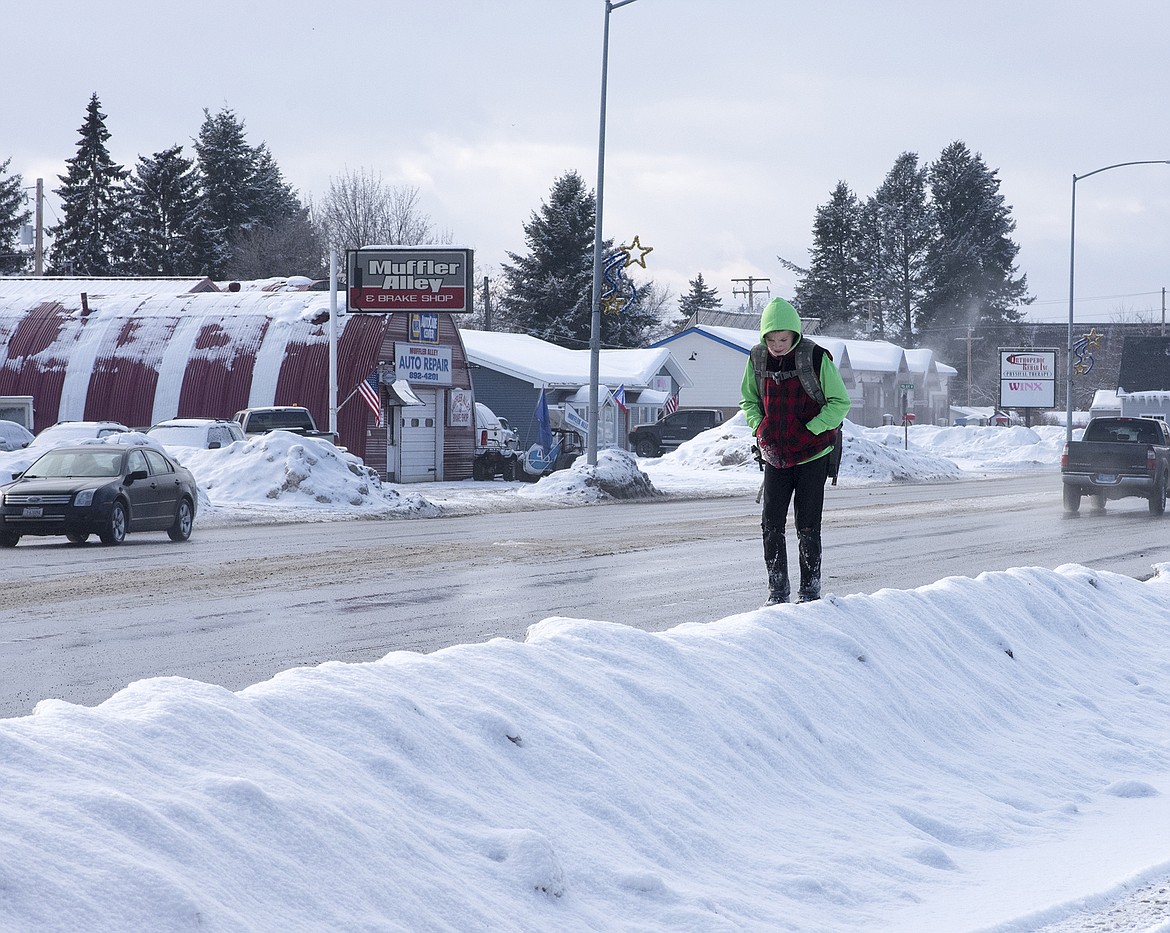 A boy who identified himself as Corbin walks on a snowbank where the sidewalk would normally be on US Highway 2 in Columbia Falls.