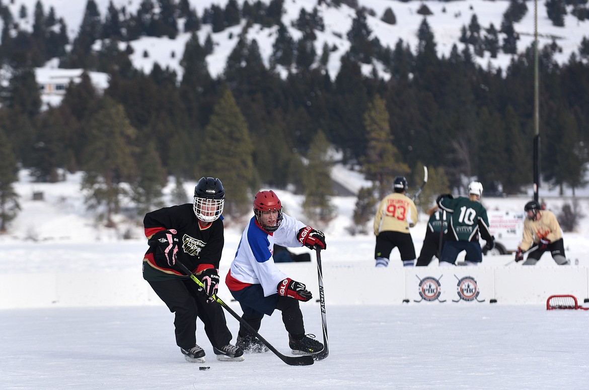 Players from the Northern Lights of Whitefish and the N.Y. Strangers from Connecticut chase down a puck during the Montana Pond Hockey Classic at Foys Lake on Friday. (Aaric Bryan/Daily Inter Lake)