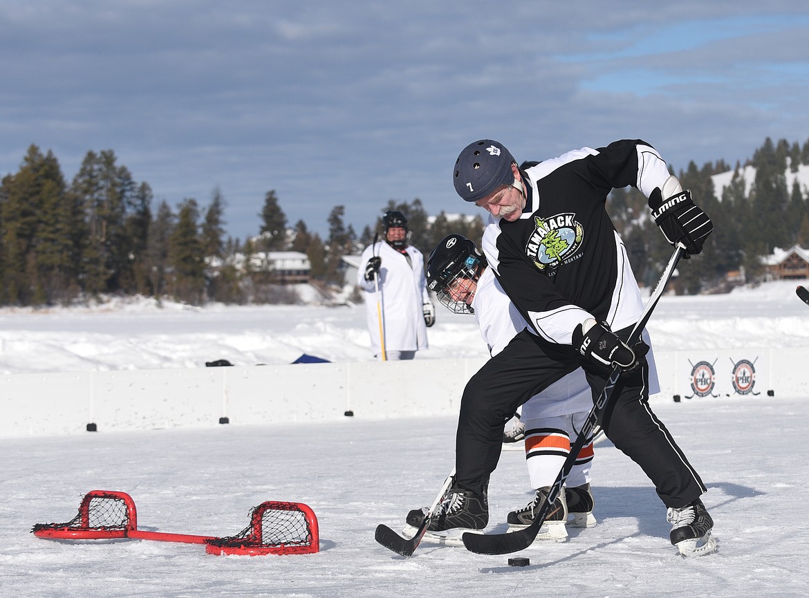 Lanny McDonald fends of a M=MA player as he scores a goal during the Montana Pond Hockey Classic at Foys Lake on Friday. (Aaric Bryan/Daily Inter Lake)