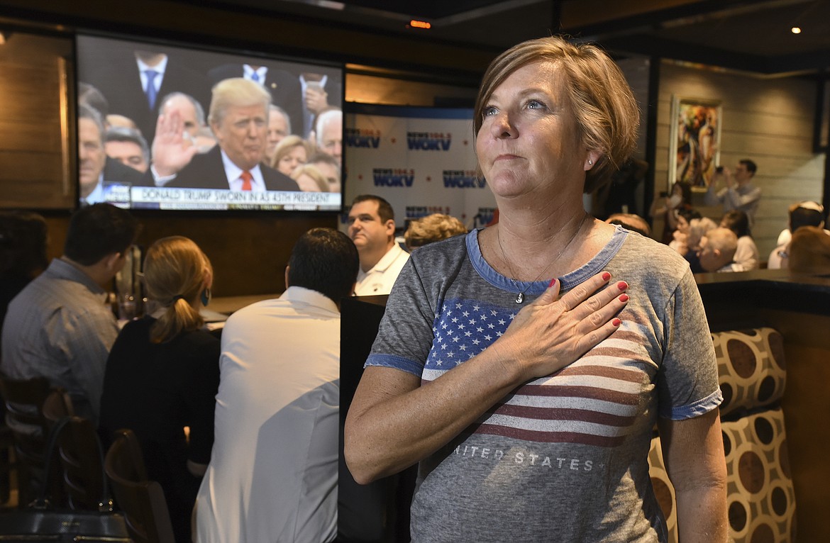 Victoria Barette from Jacksonville, Fla., holds her hand over her heart as she and other patrons watch Donald Trump take the presidential oath of office on the multiple video screens during an Inauguration Watch Party at Whiskey Jax in Marsh Landing, Fla., Friday, 20. 2017. (Bob Self/The Florida Times-Union via AP)