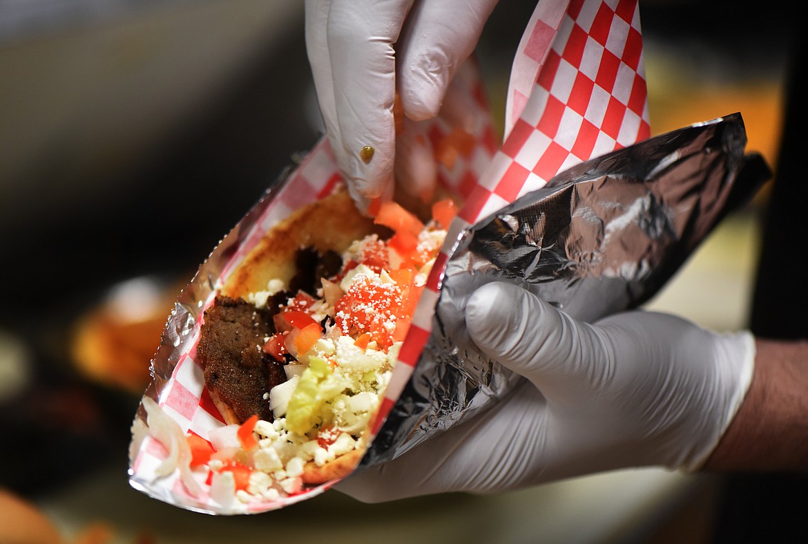 Nick Visconti piles toppings onto a Greek Gyro sandwich at Fatt Boys on Wednesday, February 1, in Kalispell. The sandwich is made on pita bread, with gyro meats (lamb and beef), shredded lettuce, diced tomatoes, onions, feta cheese and Tzatziki sauce.(Brenda Ahearn/Daily Inter Lake)