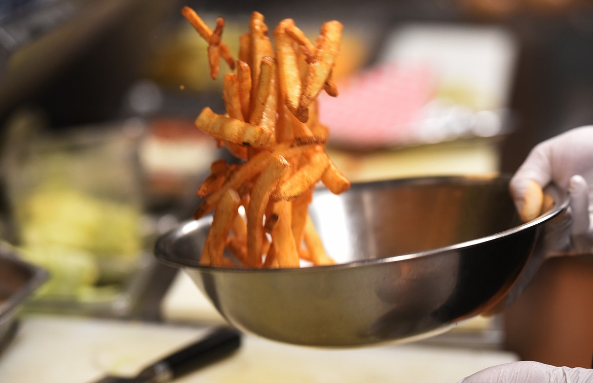 FRENCH FRIES fresh out of the fryer are topped with house seasoning before serving.