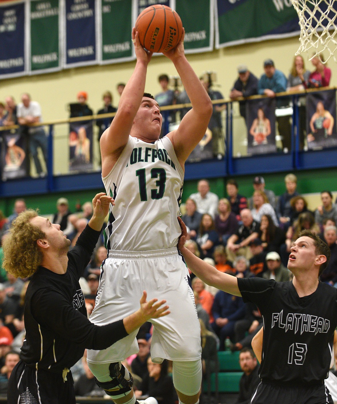 Glacier post Jaxen Hashley rises above Flathead defenders Cade White, left and Wyatt Potter for a basket. (Aaric Bryan/Daily Inter Lake)