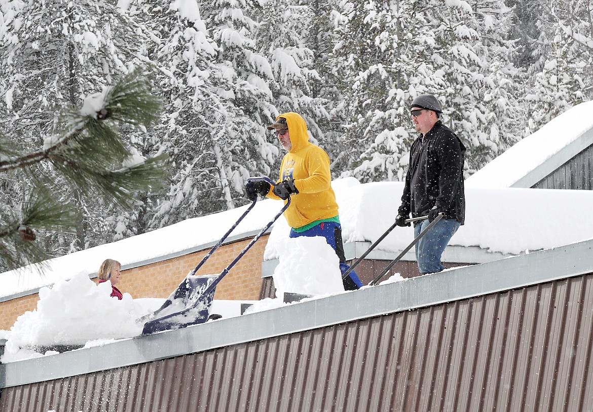 Dean Thompson, left, and Micah Germany work at shoveling the roof at Libby Elementary Monday afternoon. (Paul Sievers/TWN)