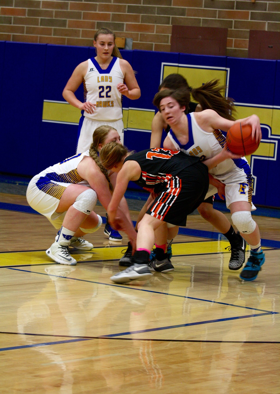 Gillian Nelson (#12) of the Lady Hawks grabs the loose ball while Sierra Curtiss (12) of the Eureka Lady Lions ends up with empty hands.