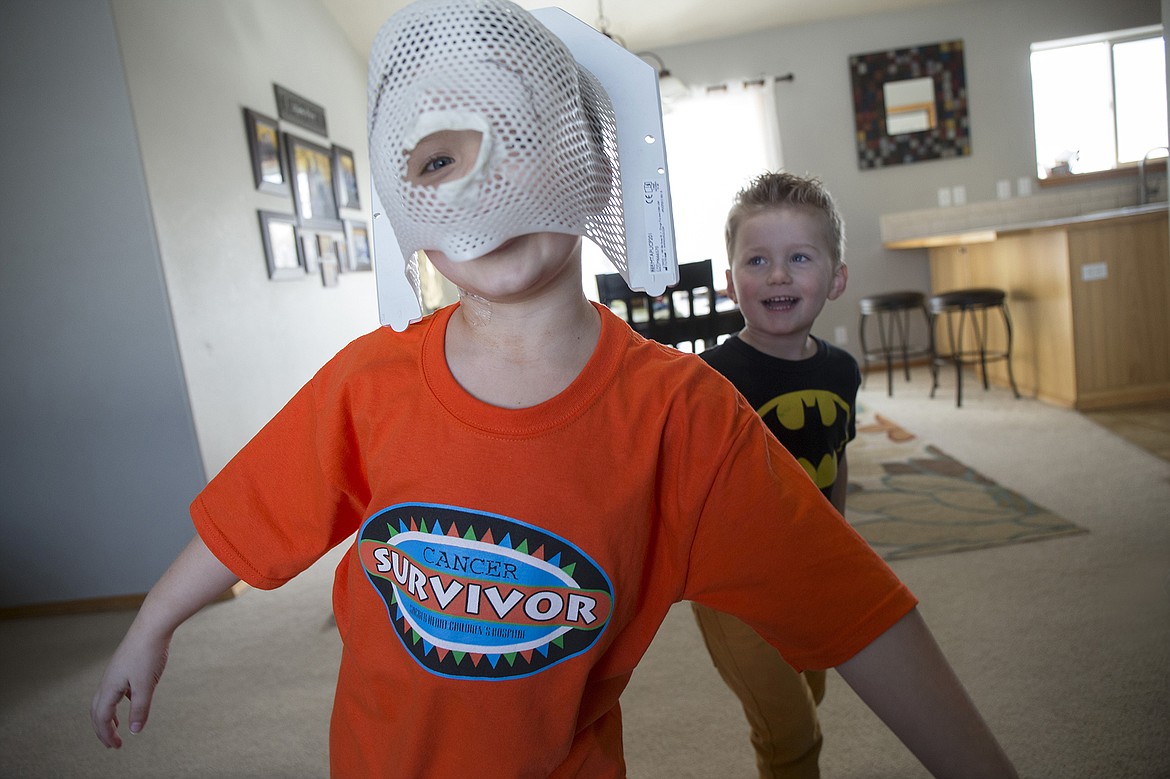 LISA JAMES/ PressTyce Fuqua, front, with his brother Jax looking on, shows the radiation mask that was made from a mold of his face after he was diagnosed with leukemia at the age of 2. The mask was worn for his 3 years and 3 months of  chemotherapy, which he completed last Thursday.