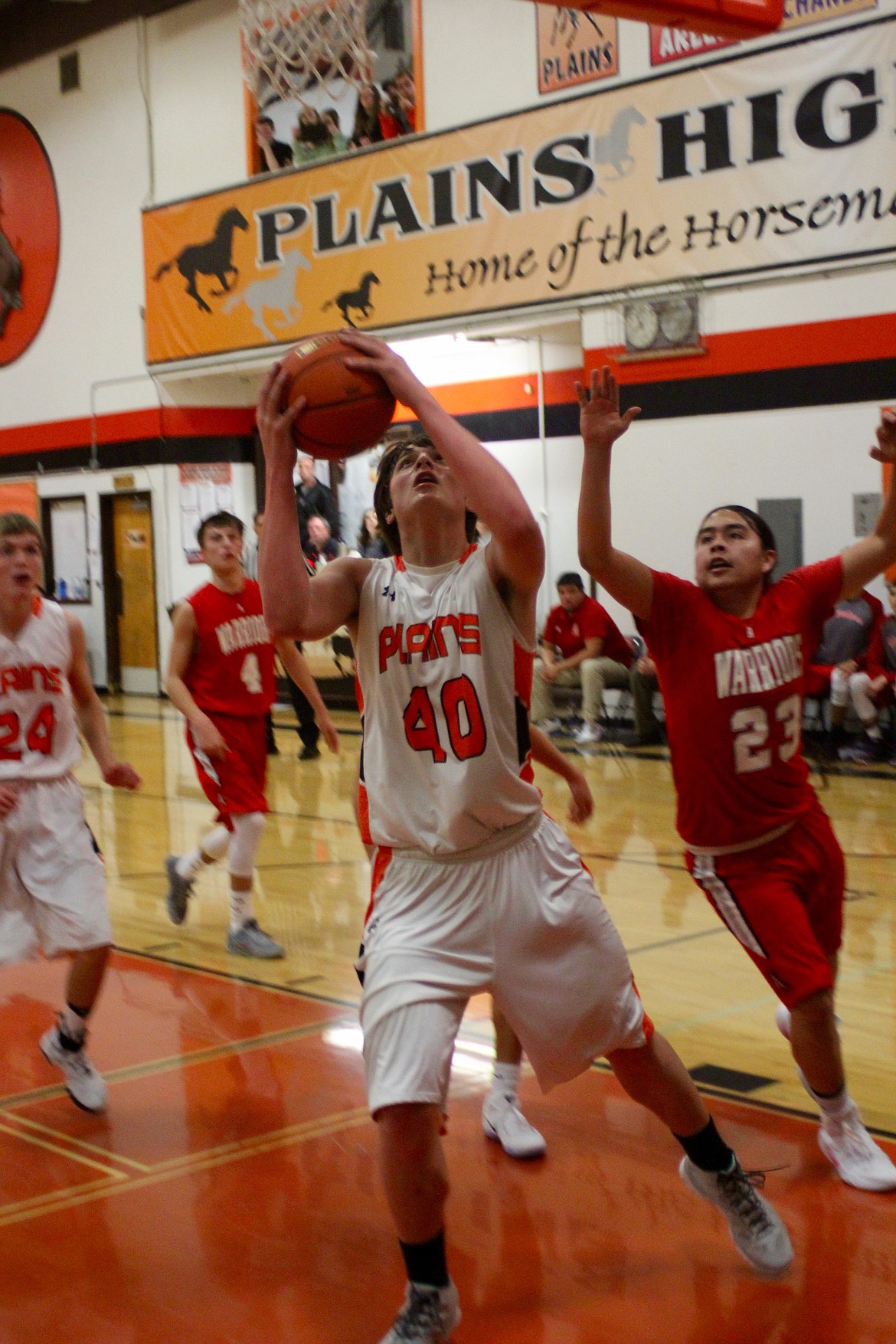 Jay VonHeeder (#40) of the Horsemen moves to the basket with the ball against the defense of Alex Moran (23), as Sam Rehbein (24) and Warriors player Philip Malatare (#4) watch.