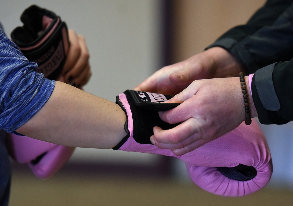 Garret Garrels helps a student with a set of pink gloves at the abbreviated boxing training on Friday, February 3, at Flathead Valley Community College.(Brenda Ahearn/Daily Inter Lake)