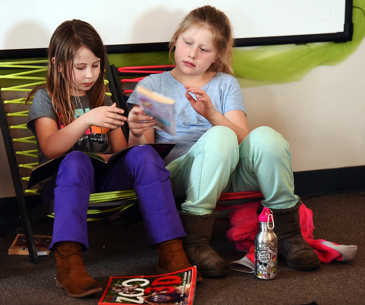 Eleanor Archie, left, hands a book to Elizabeth Barton at the start of reading time in Jennifer Watson&#146;s class on Thursday, Feb. 16, at Muldown Elementary in Whitefish.
(Brenda Ahearn/Daily Inter Lake)