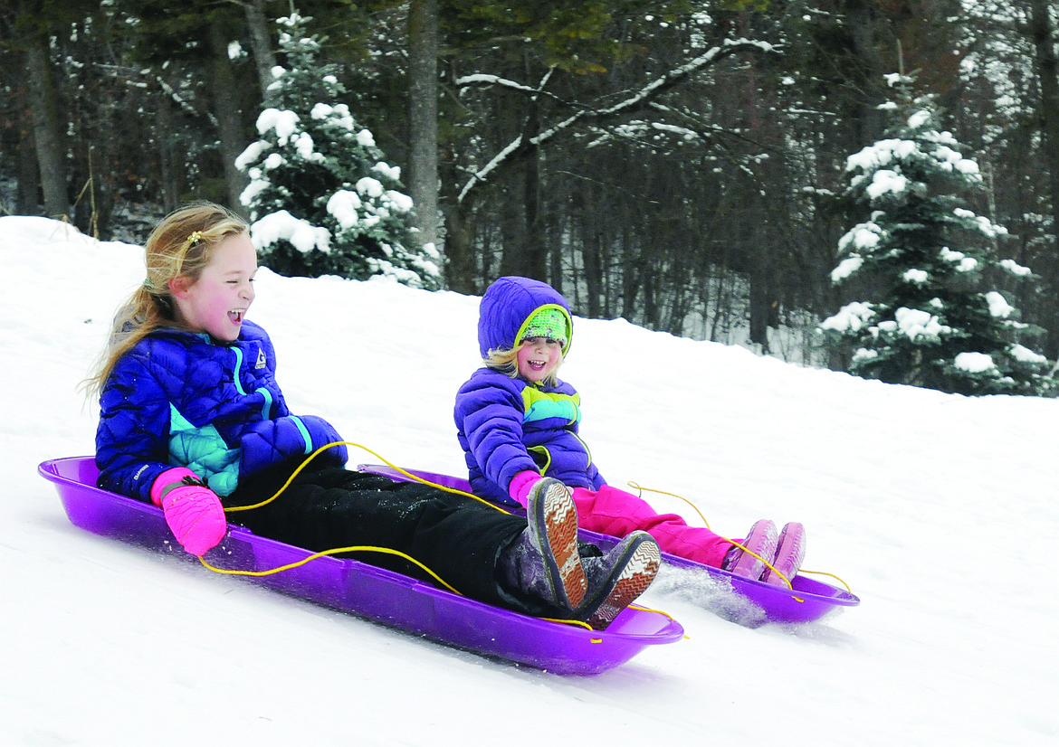 MARIAN TUCK, 6, and her 4-year-old sister Emily race down a hill at Woodland Park. (Aaric Bryan/Daily Inter Lake, file)