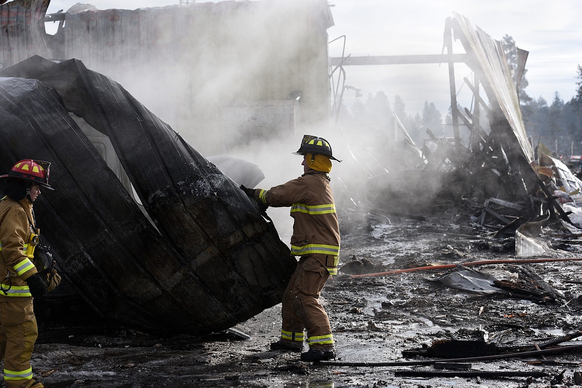 Firefighters rip off the canopy of a destroyed bus behind Reddig Equipment and Repair on U.S. 2 in Evergreen on Wednesday. (Aaric Bryan/Daily Inter Lake)