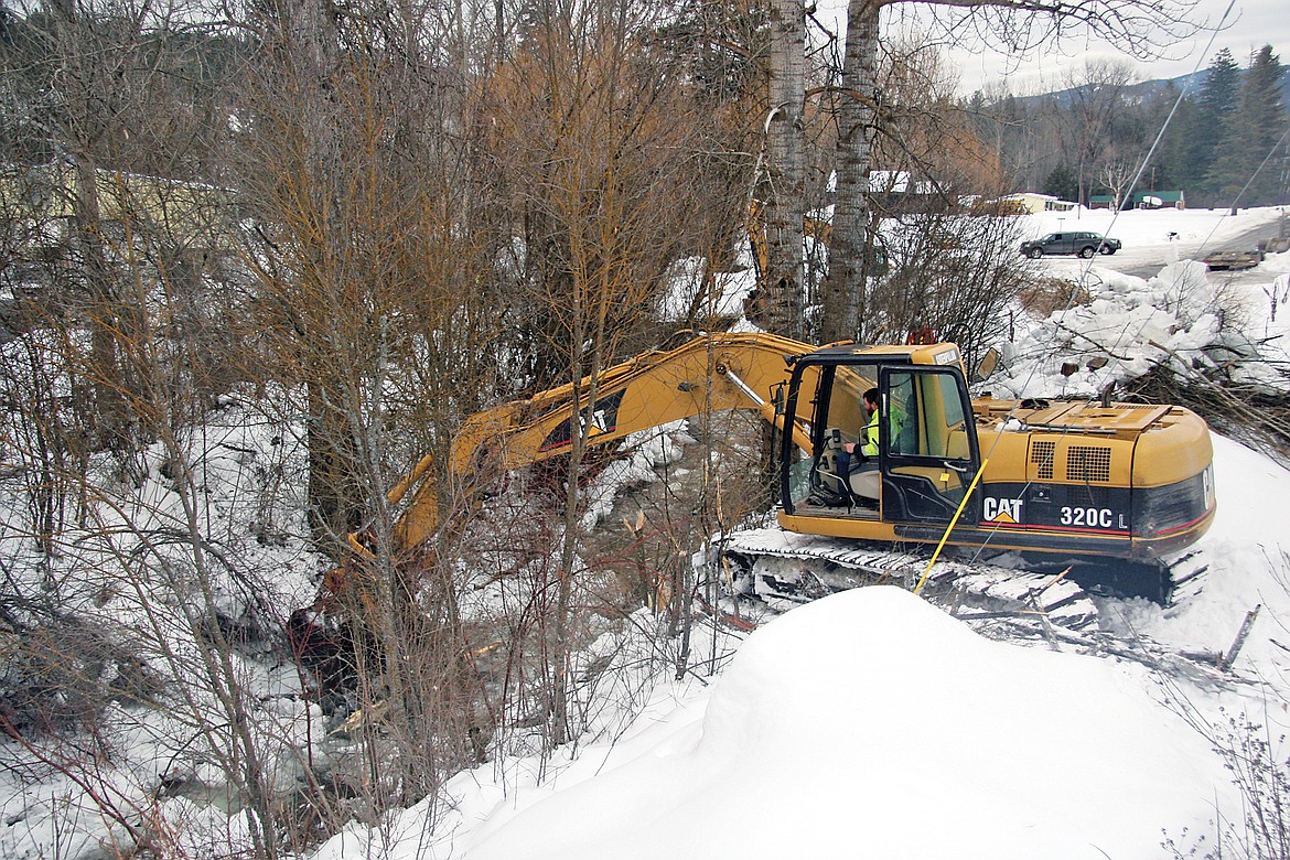 An excavator works to break up the ice that&#146;s built along the City Service Road on the Northwest side of Libby. (Bethany Rolfson/TWN)