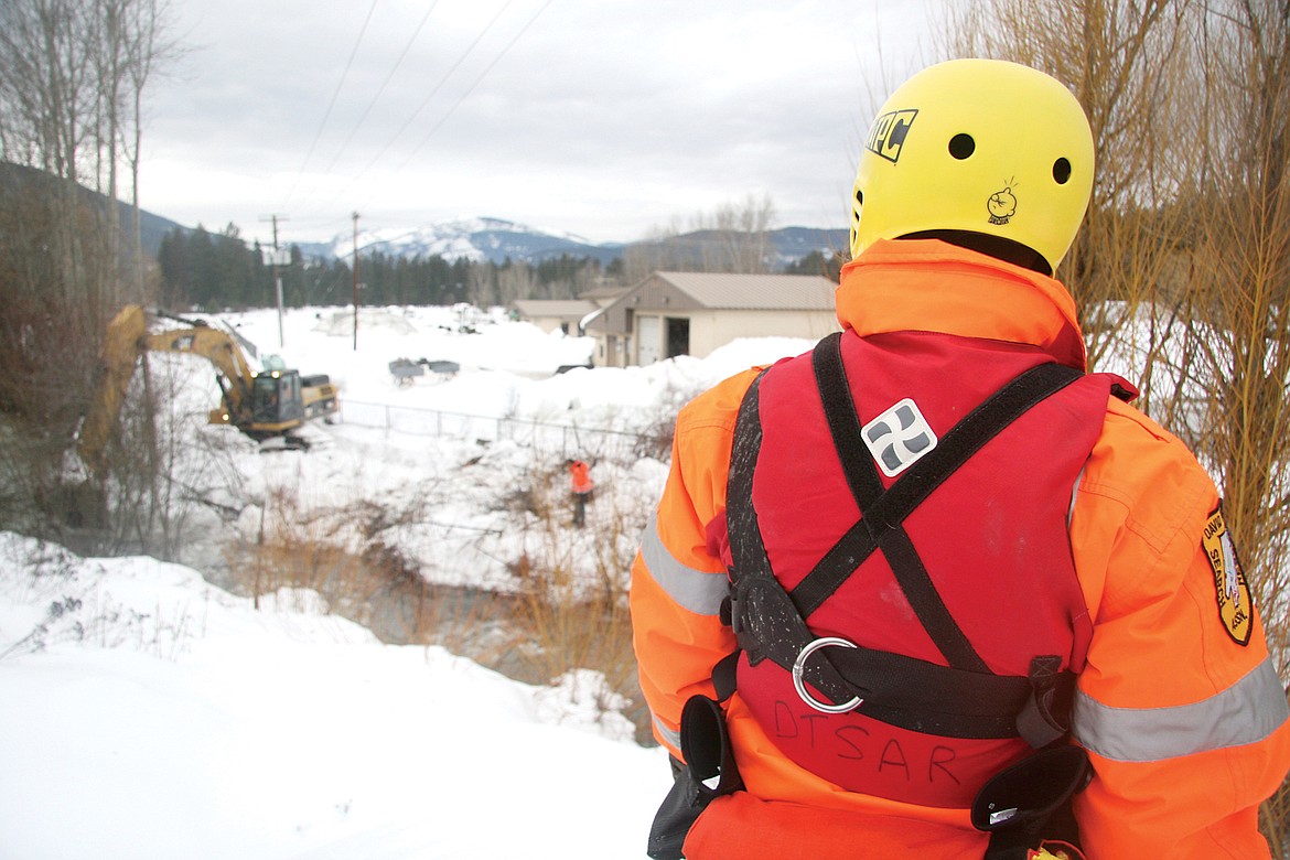 Linda Shilling, of David Thompson Search and Rescue, acting as a foreman, supervising the excavators busting ice in Flower Creek along City Service Road on the Northwest side of Libby. (Bethany Rolfson/TWN)