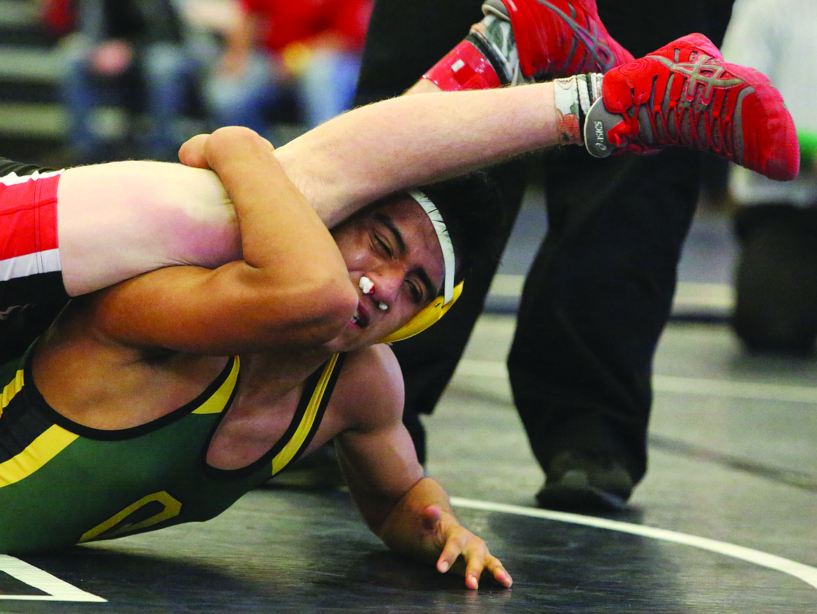 Connor Vanderweyst/Columbia Basin Herald
Quincy's Nate Ramirez hangs onto the leg of Othello's Sterling Roylance.