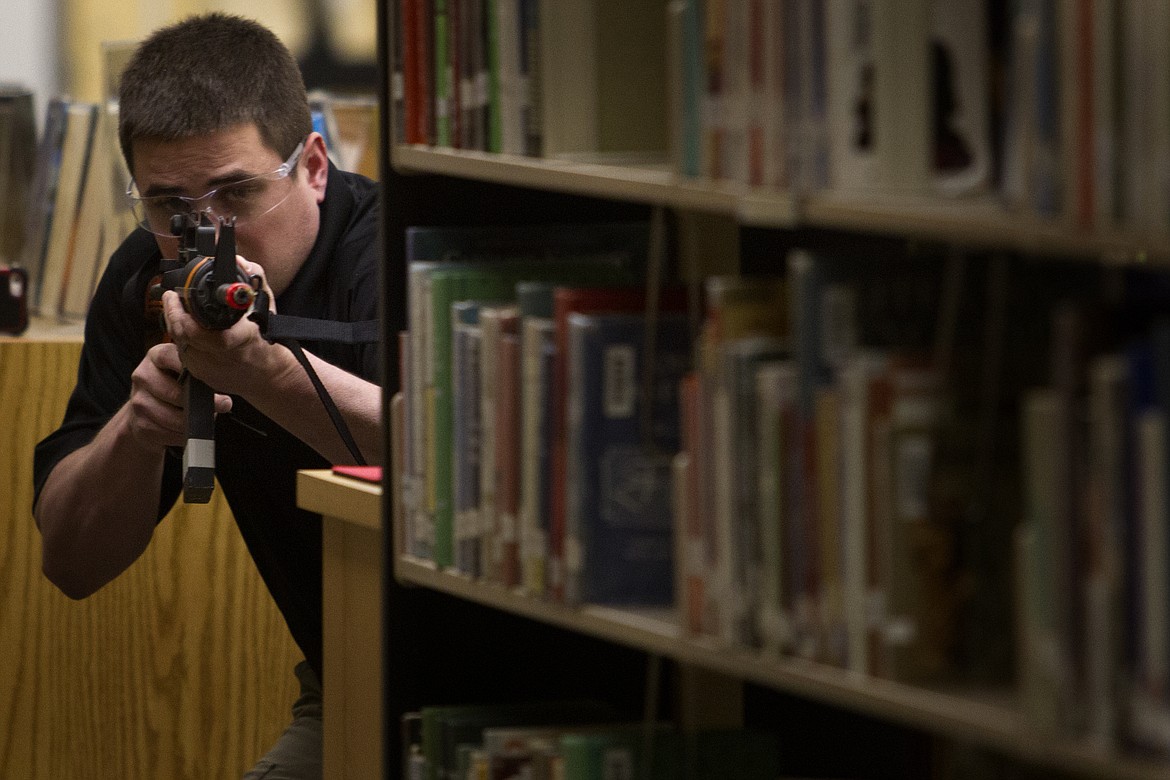 School Resource Officer Brian Hynes takes aim around a library bookshelf during active shooter training at Polson High School last week. 
(Jeremy Weber/Lake County Leader)