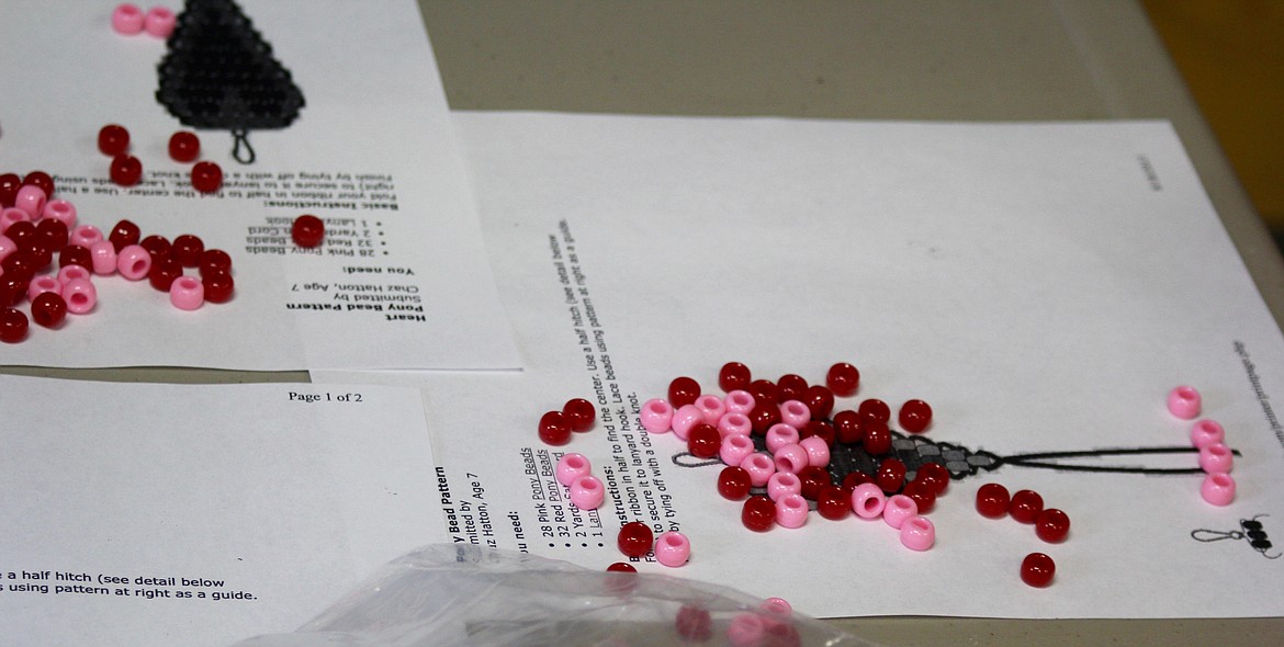 Beads and pages of directions on how to create the Beaded Heart Keychain are spread out on a table at the Plains Public Library.