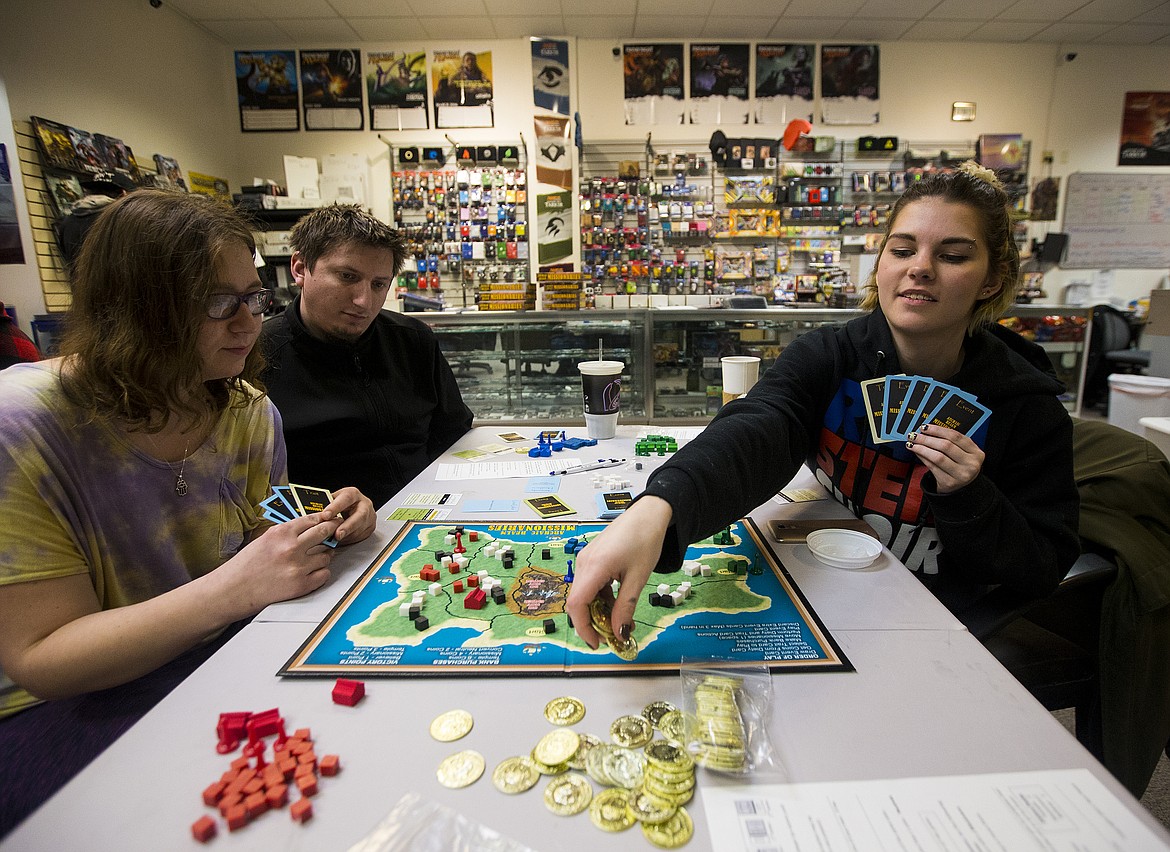 LOREN BENOIT/Press
Stephanie Billman, right, trades her gold coins to hire and place a missionary on a game board during a play-test event at Strategy and Games in the Silver Lake Mall on Monday. Also playing are Rachel Sieradzki and Cody Raugh. Four people can play &#147;Archaic Realm Missionaries,&#148; a strategy game where each player must promote their faith to inhabitants of a secluded island.